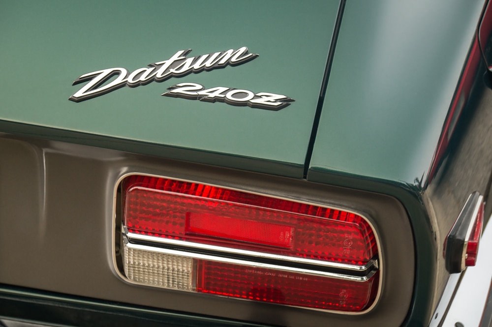 JDM คืออะไร TORONTO, CANADA 08 18 2018 โลโก้ Datsun บนท้ายรถของปี 1971 Datsun 240Z coupe รถสปอร์ตเก่าของ Racing Green ที่ทำโดย Nissan Motor Co., Ltd ในการแสดงที่การแสดงอัตโนมัติ Wheels บน Danforth